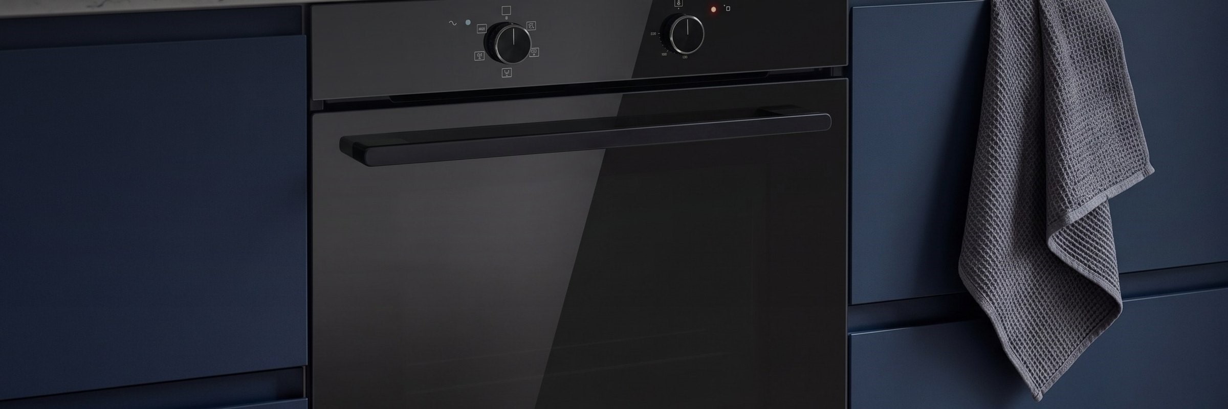 DeSantii black built-in single oven with a dark tinted glass door in a navy blue kitchen